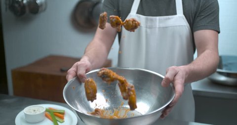 Male chef tossing chicken wings in glaze sauce closeup in ultra slow motion with 4k Phantom Flex camera