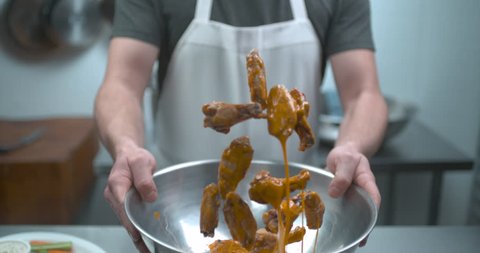 Male chef tossing chicken wings in 5 alarm hot sauce closeup in ultra slow motion with 4k Phantom Flex camera
