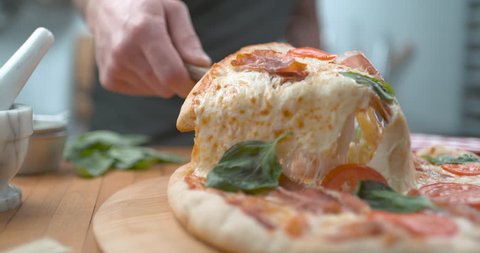 Freshly baked wood fired pizza being sliced with melty cheesy closeup ultra slow motion with 4k Phantom Flex camera