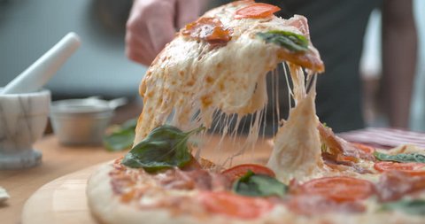 Freshly baked wood fired pizza being sliced with melty cheesy closeup ultra slow motion with 4k Phantom Flex camera