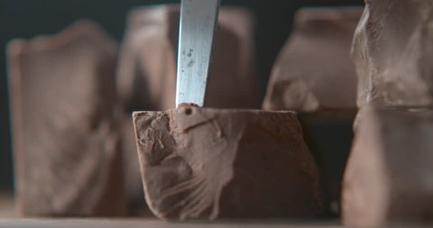 Solid milk chocolate being sliced with knife closeup ultra slow motion with 4k Phantom Flex camera