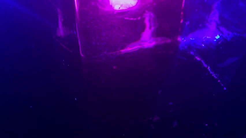 Moody and dark shoot of glitter falling down on a big block of clear ice.