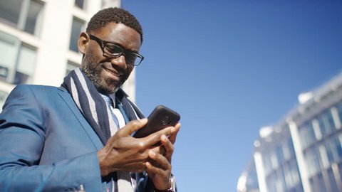 Mature black male in a suit using his phone outdoors in the city