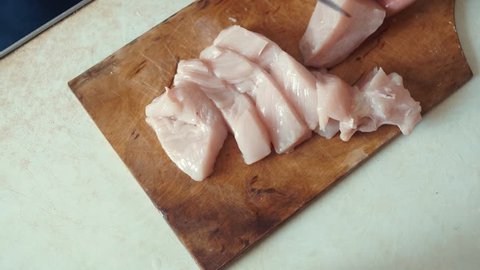 Someone is cutting raw chicken meat. Cooking food concept