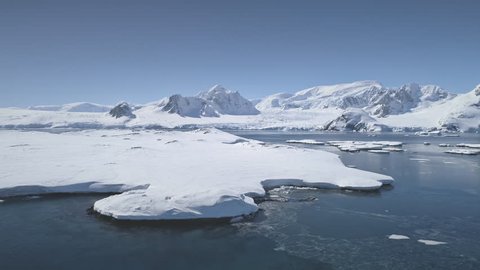 Aerial Flight Over Antarctica Shoreline, Ocean And Snow Covered Land. Drone Overview Shot Of Antarctic Continent. White Winter Landscape. Mighty Polar Mountains Background. 4k Footage.