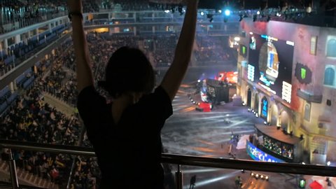 MOSCOW, RUSSIA - OCTOBER 27 2018: EPICENTER Counter Strike: Global Offensive esports event. Slow motion. Happy girl fan on a tribune at arena jumping and cheering for her favorite team. View from the