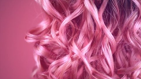 Hair. Beautiful healthy long curly dyed pink color hair close-up texture. Fashion trendy Dyed wavy hair background, coloring, extensions, cure, treatment concept. Haircare. Slow motion 4K UHD video