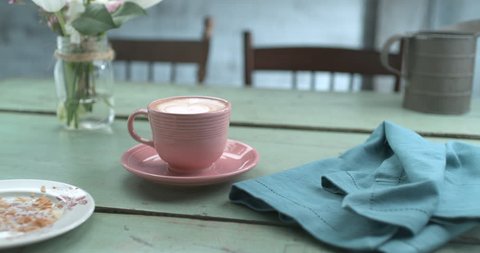 Pretty pink latte cup next to empty plate of eaten croissant and napkin ultra slow motion closeup with 4k Phantom Flex camera