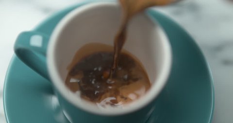 Barista pourring espresso in blue small cup in ultra slow motion closeup with 4k Phantom Flex camera