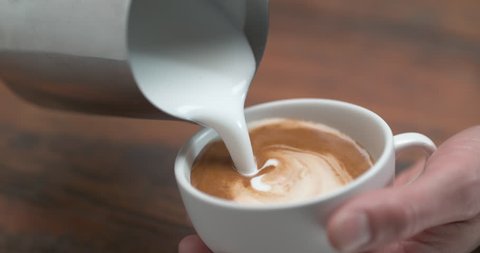 Barista making latte by pourring milk in white cup in ultra slow motion closeup with 4k Phantom Flex camera