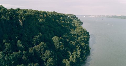 Aerial view of houses tucked away in green forest in New York during the day under overcast blue sky. Wide shot on 4K RED camera.