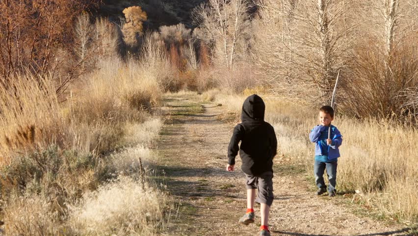 A slow motion shot of cute little brothers running through the tall golden grass on a trail at sunset | Shutterstock HD Video #1019090059