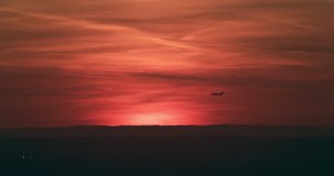 Aerial view of airplane flying in distance in New York at red sunset. Wide to Long shot on 4K RED camera.