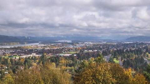 Timelapse of dramatic clouds rolling over city suburbs in fall season. Portland, Oregon neighborhoods along the Columbia River and traffic moving on I84.