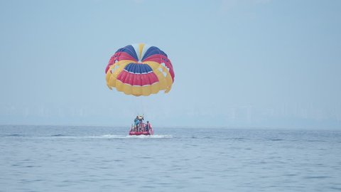 KEMER, TURKEY - May 12, Tourists have fun in the water attraction - parasailing. Man with parachute moves with motor boat.