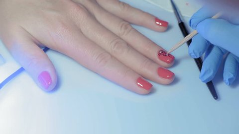 Close-up, Master Manicure Decorates the Nail on the Girl's Hand with Artificial Faceted Pebbles