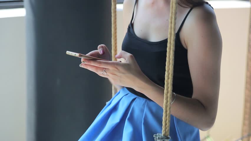 Girl of the Caucasian business. Sits in the swing room and works with a mobile phone | Shutterstock HD Video #1019105872