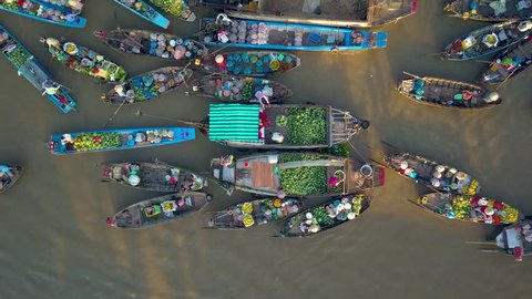 DRONE, TOP DOWN: Flying above local people doing business on the colorful floating market set on the calm murky river in the scenic Vietnamese countryside. People doing business on their wooden boats.
