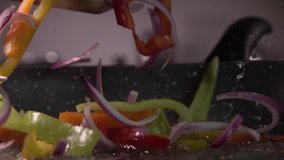 Sliced bell pepper and onion being dropped into a pan from wood, 240 fps - Powered by Shutterstock - Get 15% off with code: PIKWIZARD15