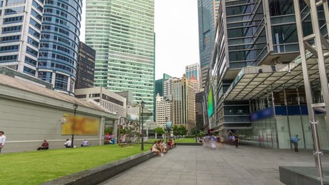 SINGAPORE - CIRCA JUNE 2018: Skyscraper towers at Raffles Place in Singapore Financial Centre timelapse hyperlapse. Green lawn. People walking around