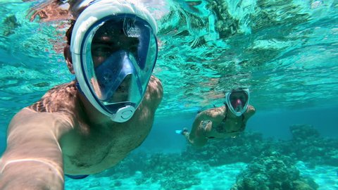 Underwater selfie - Adult couple snorkeling and seeing beautiful corals in Bora Bora