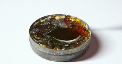 Placing melting solder wire on soldering iron tip. Close-up of hot soldering iron with smoke