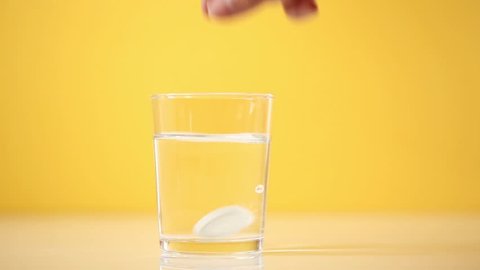 Hand dropping an effervescent tablet into a glass of water