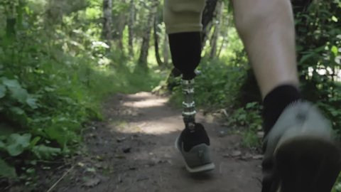 Disabled athlete with prosthetic leg running at the running track in the park