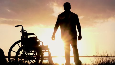 Silhouette of disabled man in wheelchair standing and walking, inspirational healing and recovery concept
