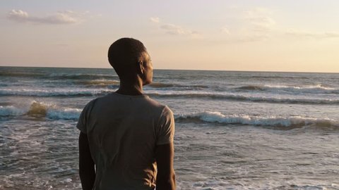Missing Africa.sad Lonely young african man observing the sunset on the sea