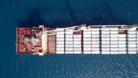 Large general cargo ship loaded with Ammonia containers - Top down aerial footage