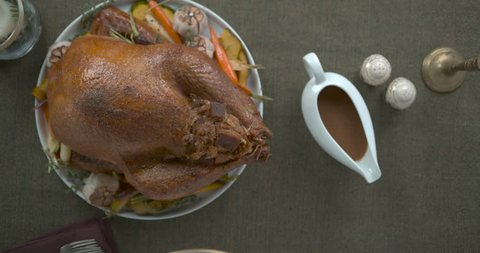 Fancy thanksgiving table with stuffed turkey, gravy, mashed potatoes, salad and jelly, on a green tablecloth, decorated with candles. Top shot in slow motion in 4K on a Phantom Flex camera.
