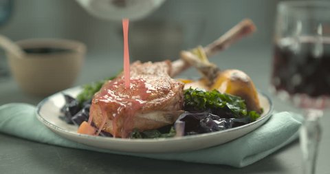 Pink sauce poured on rack of lamb in faience plate with salad and yellow turnip. Chef's Table and cooking show inspired footage. Close shot in slow motion in 4K on a Phantom Flex camera.