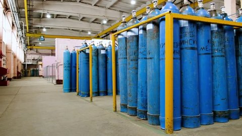 A bundle of oxygen cylinders with compressed gas secured on yellow skids in platform. Blue Oxygen tanks for industry. Liquefied oxygen production. Factory