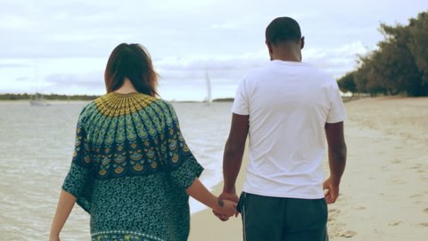 Young couple walking close to the shore holding hands and enjoying each other's company on the beach in Australia with soft day lighting. Medium shot on 4k RED camera.
