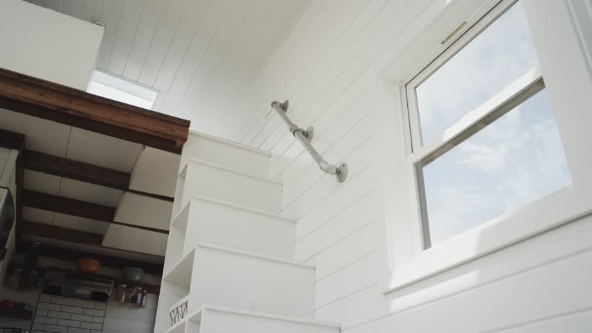 Young African American male walks down the stairs of a tiny home to the kitchen to get some coffee in slow motion