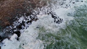 rocky coastline with crashing waves, aerial drone view