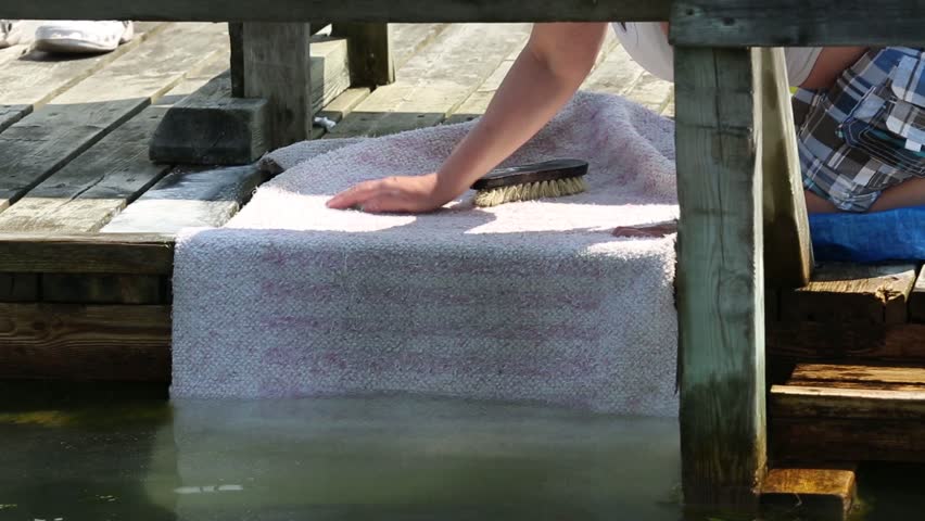 carpets drying in the sun in carpet washing place on beach, floating Dock with table to wash carpets in sea free time tradition, charcoal Pile at background.