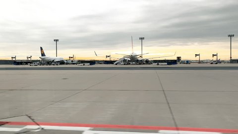FRANKFURT; GERMANY - CIRCA 2018: Sunrise at Frankfurt International Airport with planes on tarmac from Lufthansa Airlines and airport shuttle buses waiting on near aircrafts
