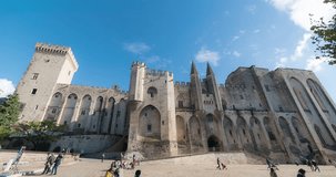 Avignon, France. Papal palace (Palais des papes) under clear blue sky.  time lapse video. Unidentified tourist passing by.  4k footage