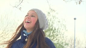 Beautiful Happy Young woman throwing snow and laughing, Happy beauty girl enjoying Winter outdoors. Laughing model having fun in winter park. Slow motion 240 fps,high speed camera. 4K UHD slow motion