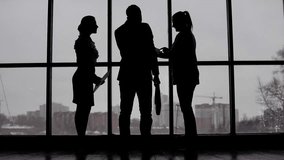 Businessman comes to two business women standing near the window and discuss the project - Powered by Shutterstock - Get 15% off with code: PIKWIZARD15