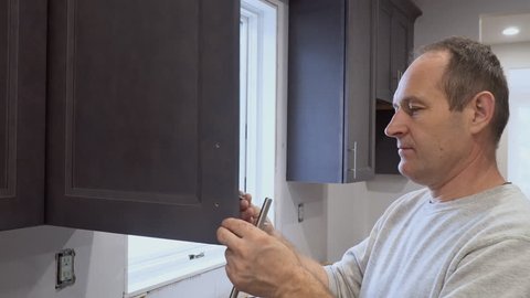 Hand on handle installation door in kitchen cabinet with a screwdriver