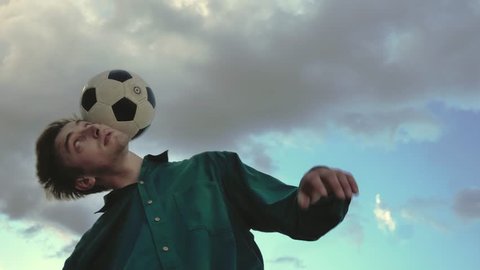 Football freestyle. Young man practices with soccer ball in parking and roof