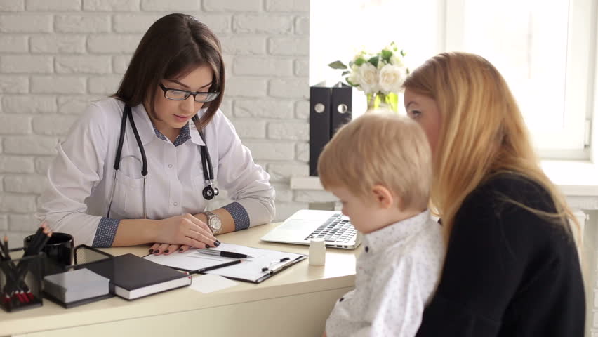 Kind and sweet woman doctor talking with a little boy in a children's clinic. Mom with a little son at a pediatrician, the doctor is very nice talking with the baby. Little boy is afraid of the doctor | Shutterstock HD Video #1019171623