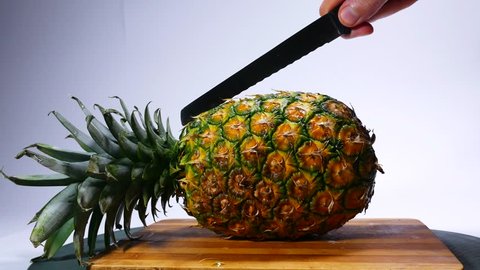 The cook cut the knife pineapple into two parts. 