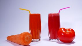 videos for tomato and carrot juice. Two glasses of pipes. Carrots and tomatoes.