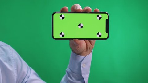 Men use smartphone in chromakey, swipe on screen, thumbs up a photo and clicks on tablet screen, green background.