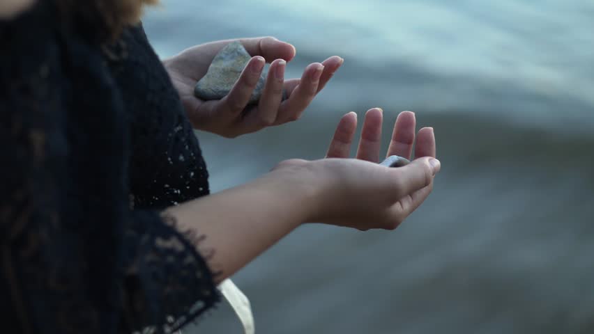 Girl facing the sea, holding in her hands the pebbles collected from the beach | Shutterstock HD Video #1019179357