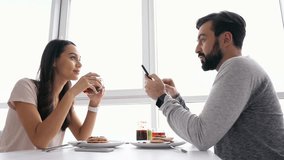 Side view of Smiling lovely couple having breakfast together and talking while sitting by the table at home